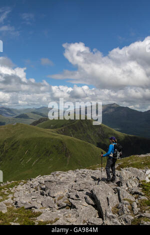 Femmina da solista escursionista guardando indietro oltre la cresta Nantle nel Parco Nazionale di Snowdonia, il Galles del Nord. Snowdon in background. Foto Stock