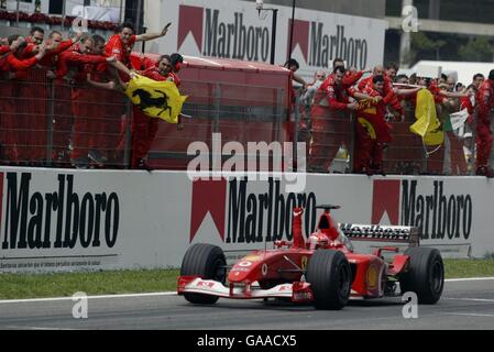 Formula uno Motoracing - Gran Premio di Spagna - gara. Michael Schumacher della Ferrari punta l'aria mentre attraversa la linea di fronte alla jubilant meccanica Ferrari per vincere la gara Foto Stock