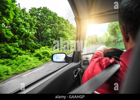 Driver maschio aziona una autovettura convertibile sulla strada del paese. La vista dalla cabina, vista posteriore, all'interno. Foto Stock