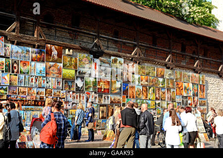 Vari stili di dipinti esposti nei pressi di Cracovia alle mura della vecchia città, per la vendita ai turisti, Cracovia in Polonia Foto Stock