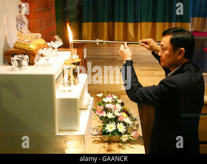 Il Dr. Thaksin Shinawatra, ex primo Ministro della Thailandia, segna il suo rispetto per Bhudda al Dhammakaya Center for Buddist Meditation a Knaphill, Surrey, un anno dopo essere stato cacciato dal suo incarico. Foto Stock