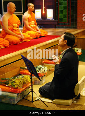 Il Dr. Thaksin Shinawatra, ex primo Ministro della Thailandia, prega con i monaci al Dhammakaya Center for Buddiste Meditation a Knaphill, Surrey, un anno dopo essere stato cacciato dall'ufficio. Foto Stock