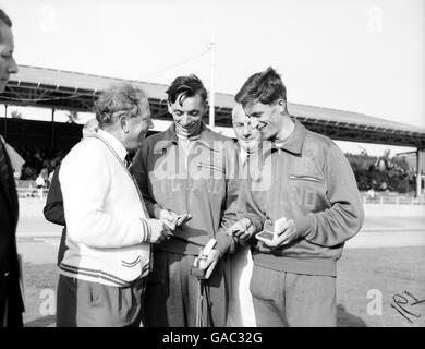 Norman Shiel (c), in Inghilterra, confronta la sua medaglia d'oro con l'argento vinto dal compagno di squadra Tommy Simpson (r), seguito dal team manager Benny Foster (l) Foto Stock