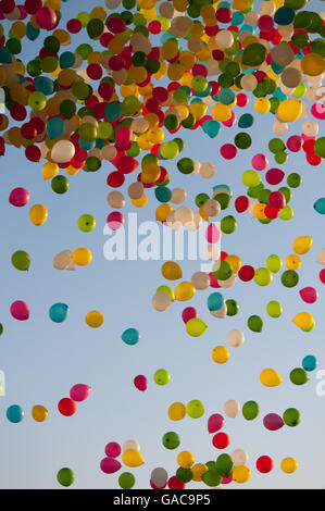 Lancio di palloncini durante una celebrazione con una varietà di palloncini colorati galleggianti nel cielo Foto Stock