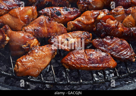 Bufali di pollo o salsa teriyaki ali cotta alla brace sul fumo barbecue grill rotondo, close up Foto Stock