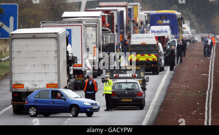 Un poliziotto istruisce i driver dell'automobile bloccati in un inceppamento di traffico a guidare il senso errato giù il motoway M8 a seguito di un incidente mortale vicino a Livingston, Scozia in cui un uomo è morto. Foto Stock