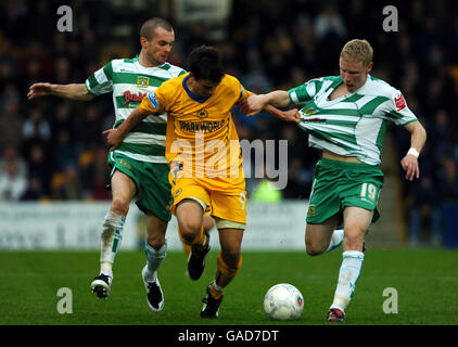 Elliott Benyon di Torquay United combatte con Nathan di Yeovil Town Jones e Criag Alcock Foto Stock