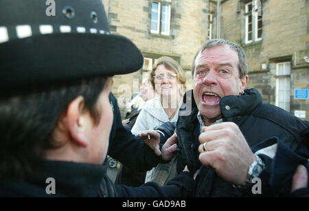 Michael Hamilton, padre di Vicky Hamilton, è trattenuto dalla polizia mentre Peter Tobin lascia Linlithgow Sheriff Court a West Lothian dopo essere stato accusato dell'assassinio di Vicky Hamilton. Foto Stock