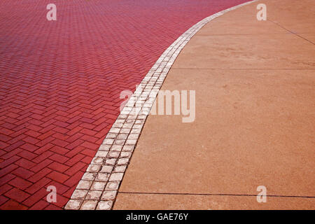 Vista ravvicinata del calcestruzzo e pavimentata in rosso i modelli e le texture sul lungomare e bianco linea centrale Foto Stock
