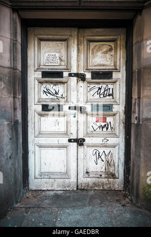 Bianco sporco vandalizzato doppie porte su un vecchio edificio Foto Stock