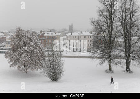 Uomo che cammina attraverso la neve in un parco a Tunbridge Wells, Kent, Regno Unito Foto Stock