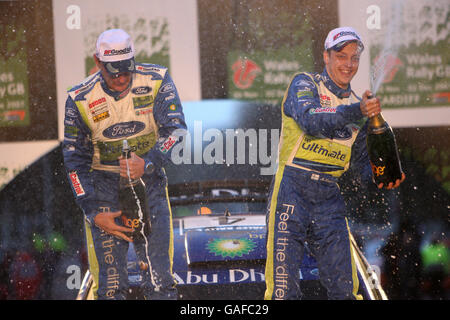Mikko Hirvonen (a destra) della Finlandia e il suo co-pilota Jarmo Lehtinen festeggiano dopo aver vinto il Wales Rally GB. Foto Stock