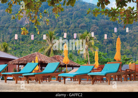 Tropicale asiatico spiaggia con lettini sotto gli alberi, Thailandia Foto Stock