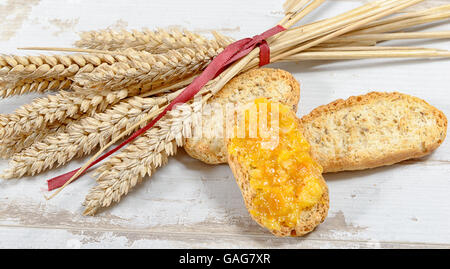 Fette di pane tostato con spighe di grano e marmellata di arancio Foto Stock
