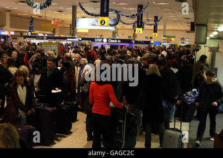 La nebbia ritarda la vacanza di Natale. I passeggeri si accodano al Terminal 1 dell'aeroporto di Heathrow dopo una fitta nebbia che ha causato numerose cancellazioni dei voli. Foto Stock