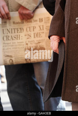 I tifosi si levano in piedi accanto alla lapide commemorativa per l'incidente aereo di Monaco. Oggi ricorre il cinquantesimo anniversario del disastro in cui sono morti 8 giocatori del Manchester United. Foto Stock