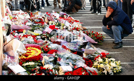 Un fan guarda i tributi florial lasciati dalla targa commemorativa per l'incidente d'aria di Monaco. Oggi ricorre il 50° anniversario del disastro in cui sono morti 8 giocatori del Manchester United. Foto Stock