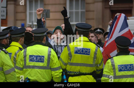 I manifestanti gridano e si lamentano dietro file di ufficiali di polizia in una parata per ricordare le vittime di Bloody Domenica a Glasgow questa mattina. Foto Stock