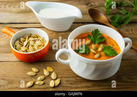 Arrosto zucca zucca minestra in crema con prezzemolo e i semi di zucca in bianco la ciotola di legno scuro dello sfondo con scacchi Foto Stock