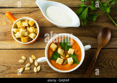 Arrosto zucca zucca minestra in crema con prezzemolo e crostini in bianco la ciotola di legno scuro di sfondo, vista dall'alto Foto Stock