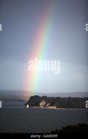 Un arcobaleno sopra il castello di Branksea (conosciuto anche come Castello di Brownsea) nel porto di Poole, Dorset, mentre le nubi della tempesta si riuniscono. Foto Stock