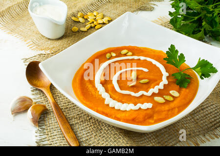 Arrosto zucca zucca minestra di verdura con crema, semi di zucca e prezzemolo in un quadrato bianco piastra su tela Foto Stock