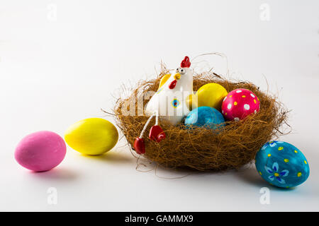 Gallina di porcellana in un nido con dipinto di uova di Pasqua su uno sfondo bianco. Close up. Sfondo di pasqua. Sfondo di pasqua. Pasqua s Foto Stock