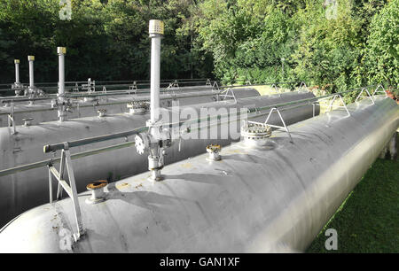 Pipeline di grandi dimensioni e di una valvola di sicurezza oltre il gigantesco serbatoio per lo stoccaggio di gas infiammabile nell'impianto industriale Foto Stock