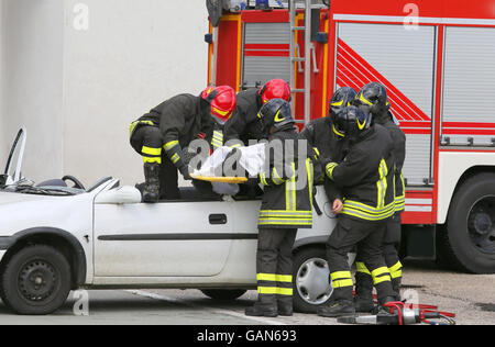 Coraggiosi vigili del fuoco alleviare un infortunato dopo incidente di automobile Foto Stock