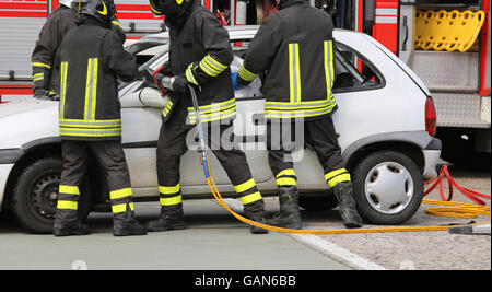 Coraggiosi vigili del fuoco alleviare un ferito dopo un incidente durante una sessione di prove per la stazione dei vigili del fuoco Foto Stock