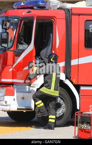Coraggiosi vigili del fuoco in azione salta giù rapidamente dal firetruck durante un'emergenza Foto Stock