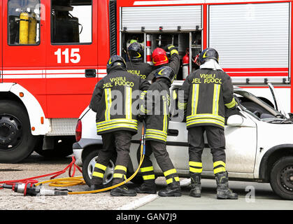 Coraggiosi vigili del fuoco alleviare un ferito dopo un incidente durante una sessione di prove per la stazione dei vigili del fuoco Foto Stock