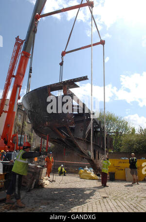 I lavoratori manovrano il contatore del Cutty Sark a terra dopo che è stato rimosso dalla poppa della nave con gru, in preparazione al suo restauro da parte del progetto di conservazione di Cutty Sark. Foto Stock