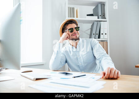 Giovani felici bel uomo seduto al tavolo in ufficio Foto Stock