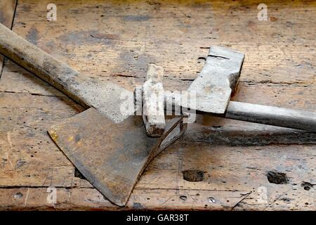 Gli antichi strumenti piccoli ax e grande martello sul vecchio banco in legno Foto Stock