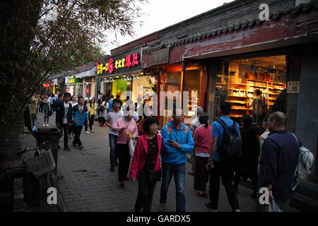 Il popolo cinese e i turisti a piedi di sera in un vicolo di una storica hutong con un sacco di piccoli negozi. Nanluoguxiang Hutong di Pechino, Cina. Foto Stock