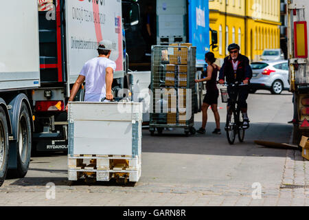 Motala, Svezia - 21 Giugno 2016: Giovani maschi adulti utilizzando un carrello per il trasporto di un bianco cassa in legno verso un carrello per furt Foto Stock