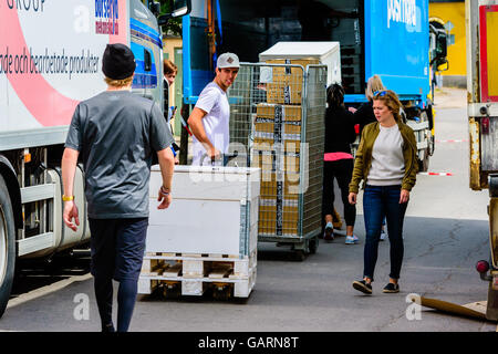Motala, Svezia - 21 Giugno 2016: Giovani maschi adulti utilizzando un carrello per il trasporto di un bianco cassa in legno verso un carrello per furt Foto Stock
