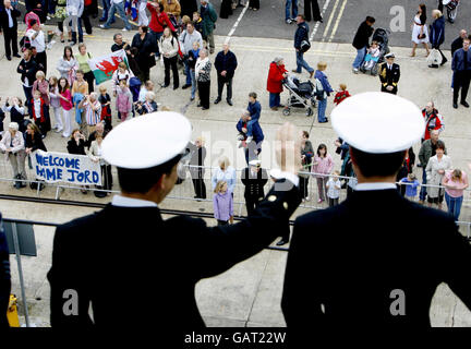 Un ufficiale saluta con la sua famiglia dal ponte di volo di HMS Illustrious mentre la nave ritorna alla base navale di Portsmouth dopo quattro mesi di spiegamento all'Oceano Indiano dove ha diretto la missione navale Orion 08. La portaerei della Royal Navy al centro di uno scandalo di "foto inappropriate" è tornata oggi al suo porto di casa dopo un dispiegamento di quattro mesi incline a un errore. Foto Stock