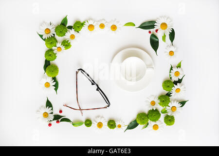 Tazza di caffè o tè e bicchieri con corona frame da camomilla e fiori di crisantemo, ficus foglie mature e rowan su whi Foto Stock