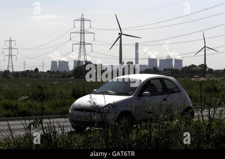 Un'auto passa davanti alle turbine eoliche nello Yorkshire orientale sullo sfondo della centrale elettrica di Drax. Foto Stock