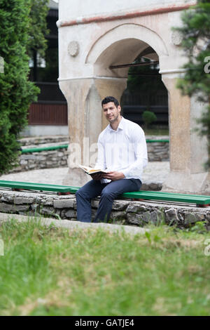 Umile uomo musulmano è la lettura del Corano all'aperto Foto Stock