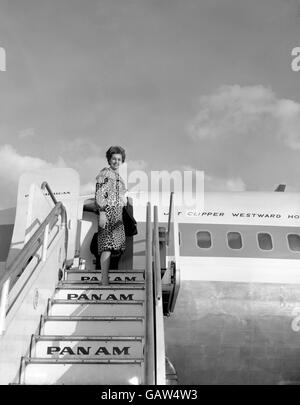 In un cappotto di pelle di leopardo e senza covoni, l'attrice Cyd Charisse si trova oggi (mercoledì) a far parte di un Clipper a getto pan americano all'aeroporto di Londra, sulla sua strada per Hollywood dopo tre mesi di riprese nel Regno Unito. Foto Stock