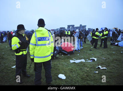 La polizia è presente sul sito come i rivelatori cantano nel frizzle di mattina presto come il maltempo e la pioggia impediscono il sole che splende la mattina del solstizio estivo a Stonehenge, Wiltshire. Foto Stock