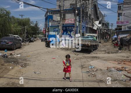 Pechino, Cina. 1 Luglio, 2016. Una bambina cammina sulla strada di urban-villaggio. Un urbano-villaggio che si trova a sud del quarto anello stradale di Pechino. La gente del posto viene tirato verso il basso i loro cottage originali e costruito in 5 o 6 piani di semplici edifici in affitto ai lavoratori migranti come il più economico camera noleggio di circa 600RMB ( circa USD 60), appartamento attraversata la strada sono vendute per circa 50.000 RMB (circa USD7497) per metro quadrato. Come comuni, infrastrutture urbane-villaggi non sono buone, acqua e sistema fognario sono il problema principale. © Jiwei Han/ZUMA filo/Alamy Live News Foto Stock