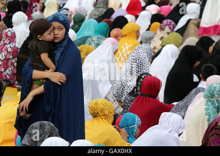 Quezon City, Filippine. 6 Luglio, 2016. Una donna musulmana tiene il suo bambino prima di offrire preghiere durante le celebrazioni dell'Eid al-Fitr in Quezon City, Filippine, Luglio 6, 2016. Eid al-Fitr segna la fine dei musulmani il mese di digiuno del Ramadan. Credito: Rouelle Umali/Xinhua/Alamy Live News Foto Stock