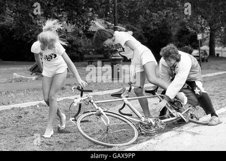 Il presentatore di Blue Peter Peter Duncan aiuta la ragazza del Consiglio del tè Sarah Oakes, a sinistra, dopo essere caduta da una bicicletta tandem, mentre ha lanciato la maratona del ciclo di Raleigh Charity Ride a Hyde Park. Foto Stock