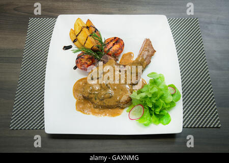 Carne di maiale alla griglia bistecche, patate al forno e insalata di verdure. Foto Stock