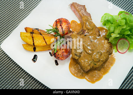 Carne di maiale alla griglia bistecche, patate al forno e insalata di verdure. Foto Stock