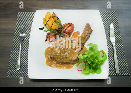 Carne di maiale alla griglia bistecche, patate al forno e insalata di verdure. Foto Stock